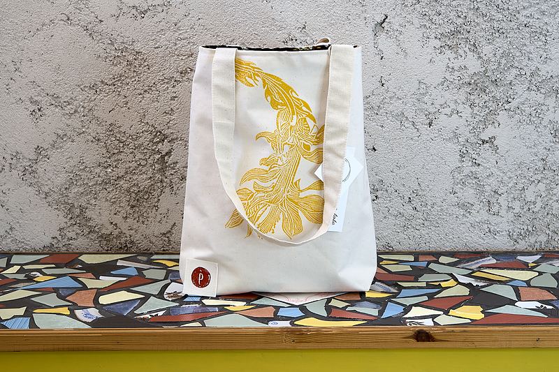 Tall natural canvas tote printed in ochre with a koi, the print running up over the strap.